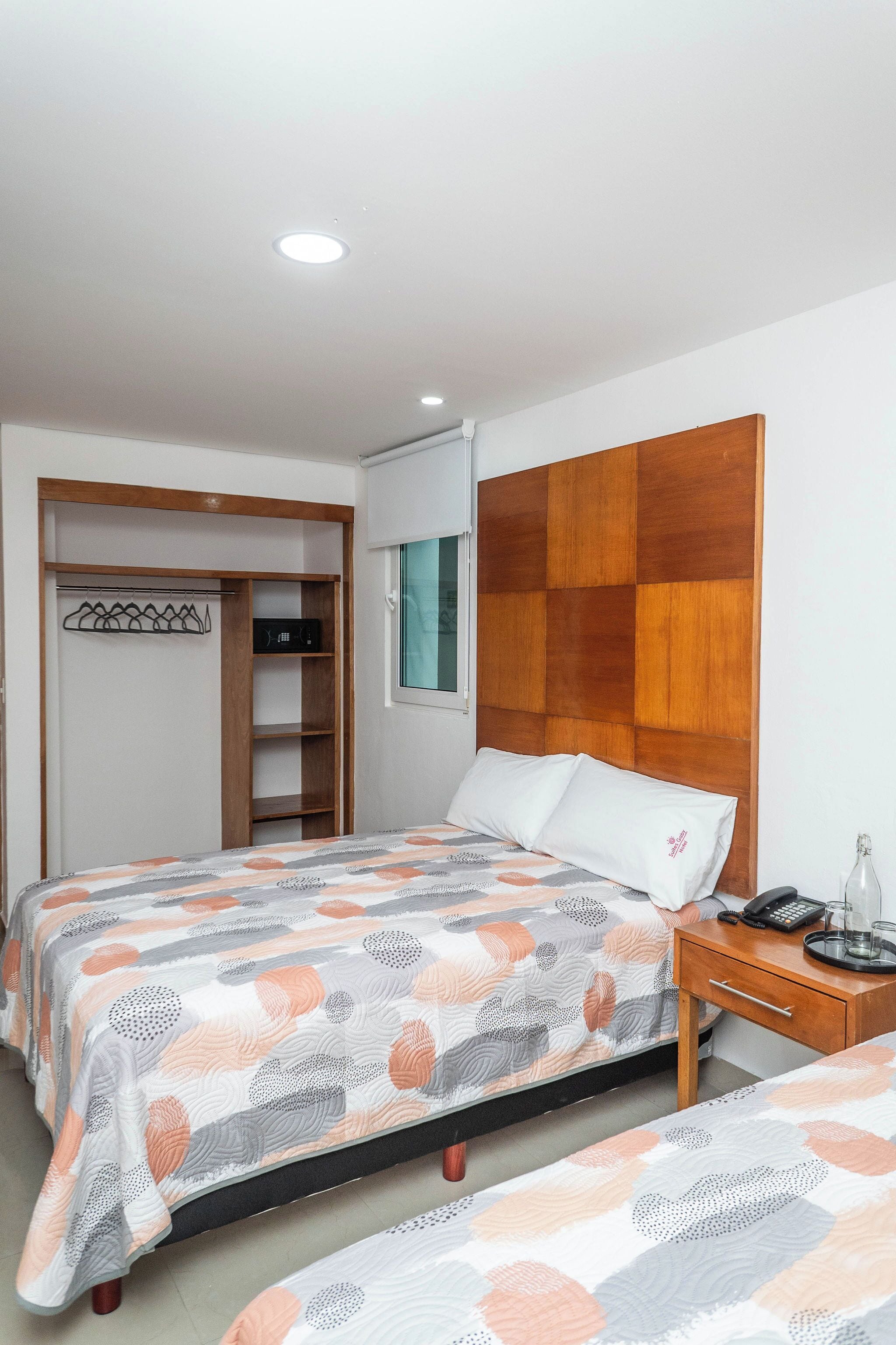 A bedroom with a bed, a bedside table, a wardrobe, and a wooden headboard.