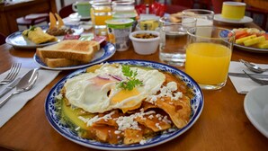 A breakfast table with plates of food, a glass of orange juice, and various condiments. - Suites Gaby Cancun (Cancun)