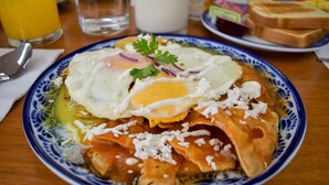 A plate of food with a poached egg, cheese, and sauce on a blue and white patterned plate. - Suites Gaby Cancun (Cancun)