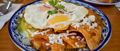 Un plato de comida con un huevo pochado, queso y salsa, sobre un plato azul y blanco con estampado.