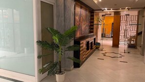 A modern lobby with a large potted plant, a fireplace, and a decorative wall. - Tunisie Confort (Tunis)