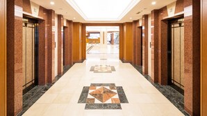 A hotel corridor with a skylight, marble flooring, and elevator doors. - Hotel Mystays Sapporo Aspen (Sapporo)