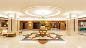 A spacious lobby with a central chandelier, a reception desk, and a decorative floor pattern. - Hotel Mystays Sapporo Aspen (Sapporo)