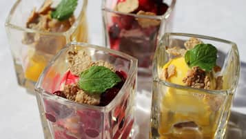 Drei Gläser mit Dessert, Obst und Streuseln, garniert mit Minzblättern.