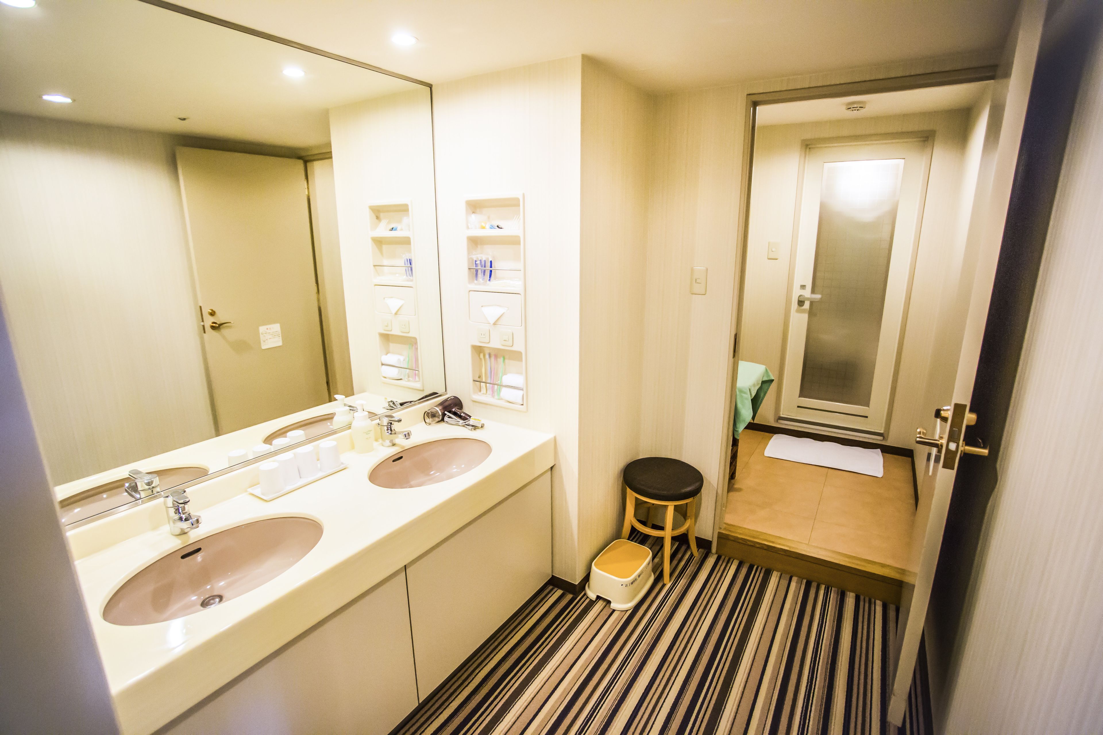 A bathroom with two sinks, a mirror, and a toilet.