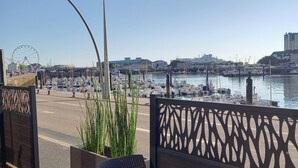 A dining table with a meal, overlooking a marina with boats and a Ferris wheel. - LOGIS La Régence (Cherbourg-en-Cotentin)