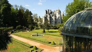 A large, historic building with a symmetrical garden layout, including a central fountain and manicured lawns. - LOGIS La Régence (Cherbourg-en-Cotentin)
