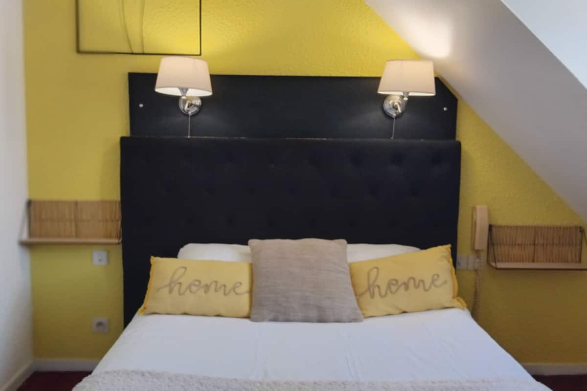 Un dormitorio con cama, dos lámparas de noche y cabecero.