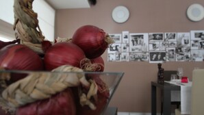 A glass bowl with red onions on a table in a room with a dining table and chairs, a wall with framed pictures, and a plate on the wall. - DA ELDA natural retreat (Ledro)