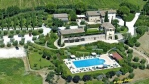 Vista aérea de una extensa propiedad con varias construcciones, una piscina y jardines cuidados.