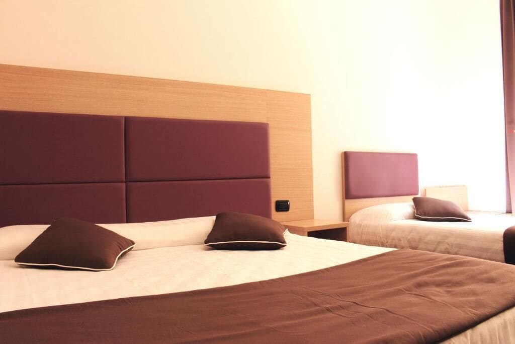 Ein Hotelzimmer mit zwei Betten, jeweils mit Kopfteil und Kissen.