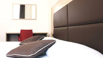 Una habitación de hotel con una cama grande, cabecero de madera, una silla roja y un espejo en la pared.