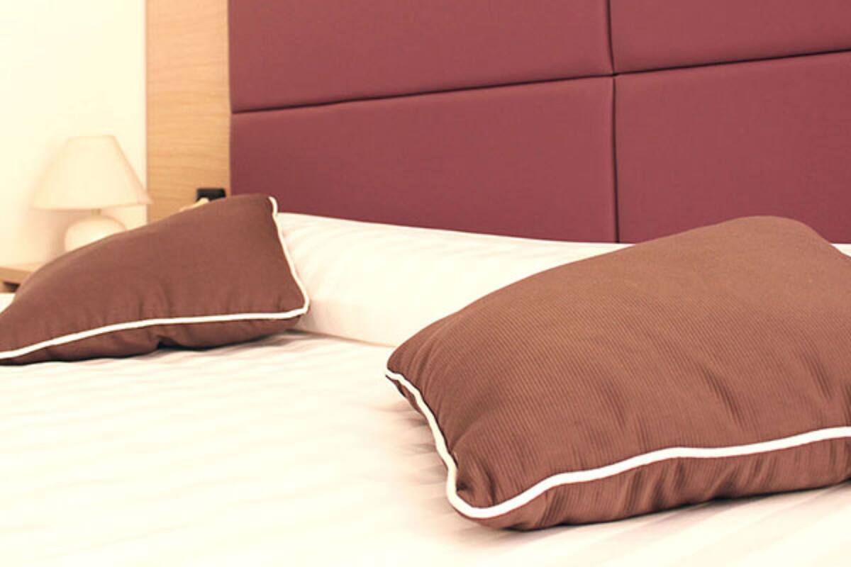 Uma cama com cabeceira de madeira e duas almofadas marrons.