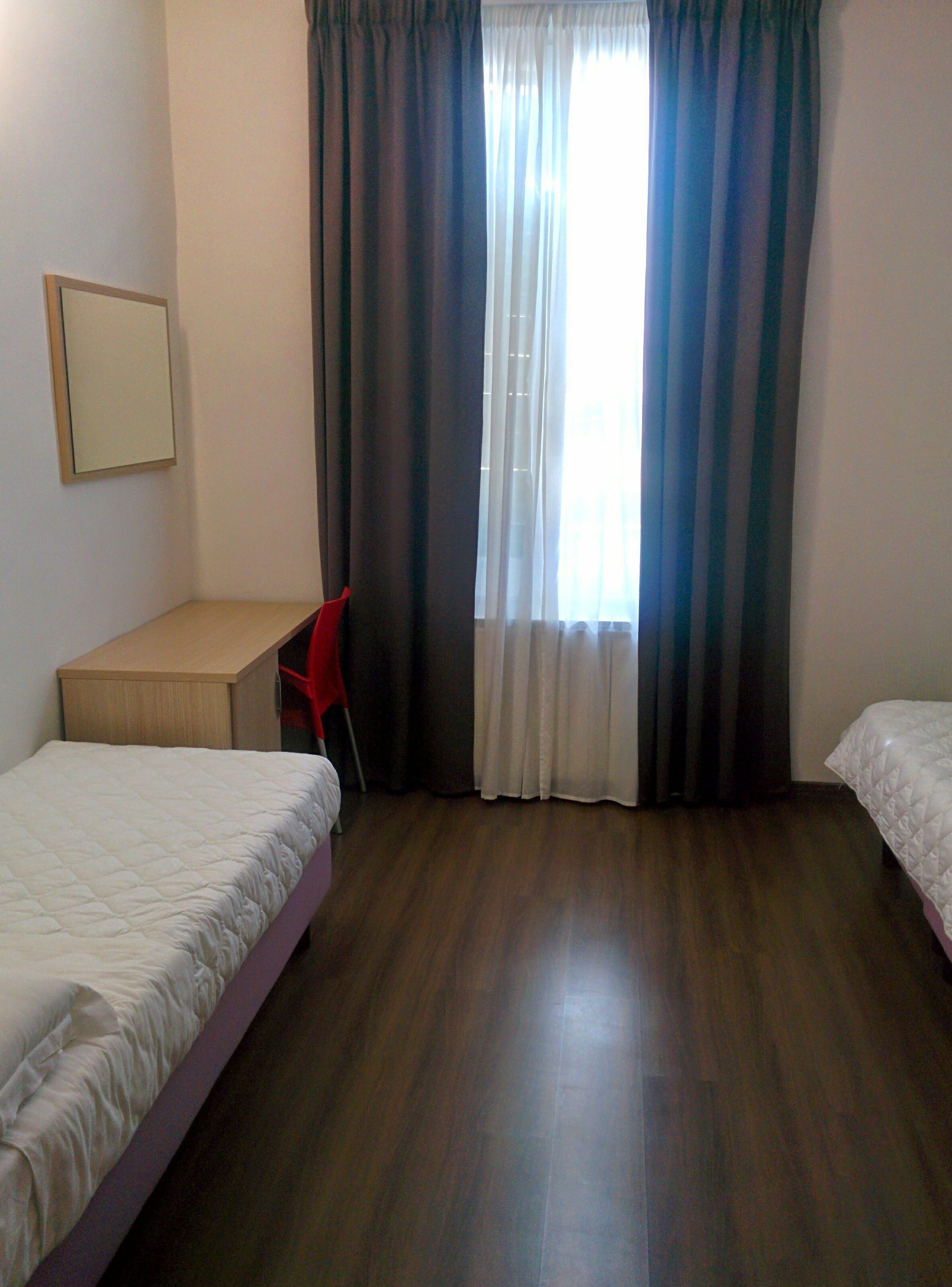 A bedroom with two beds, a desk, and a chair.
