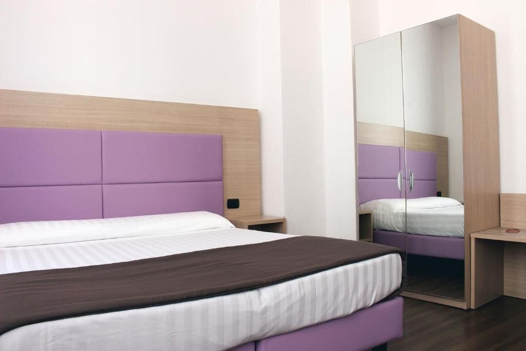 A bedroom with a bed, a wardrobe, and a nightstand.