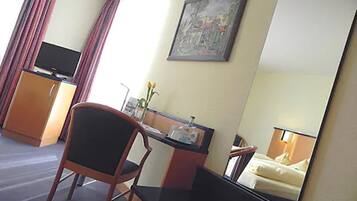 Ein Hotelzimmer mit Schreibtisch, Stuhl, Fernseher und einem Bett mit Nachttisch.