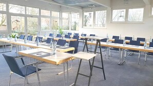 Ein Konferenzraum mit mehreren Tischen, Stühlen und Wasserflaschen.