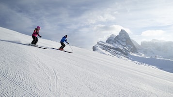 A snowy mountain slope with skiers.
