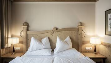 Un lit double avec du linge de lit blanc, deux lampes de chevet et une tête de lit en bois.