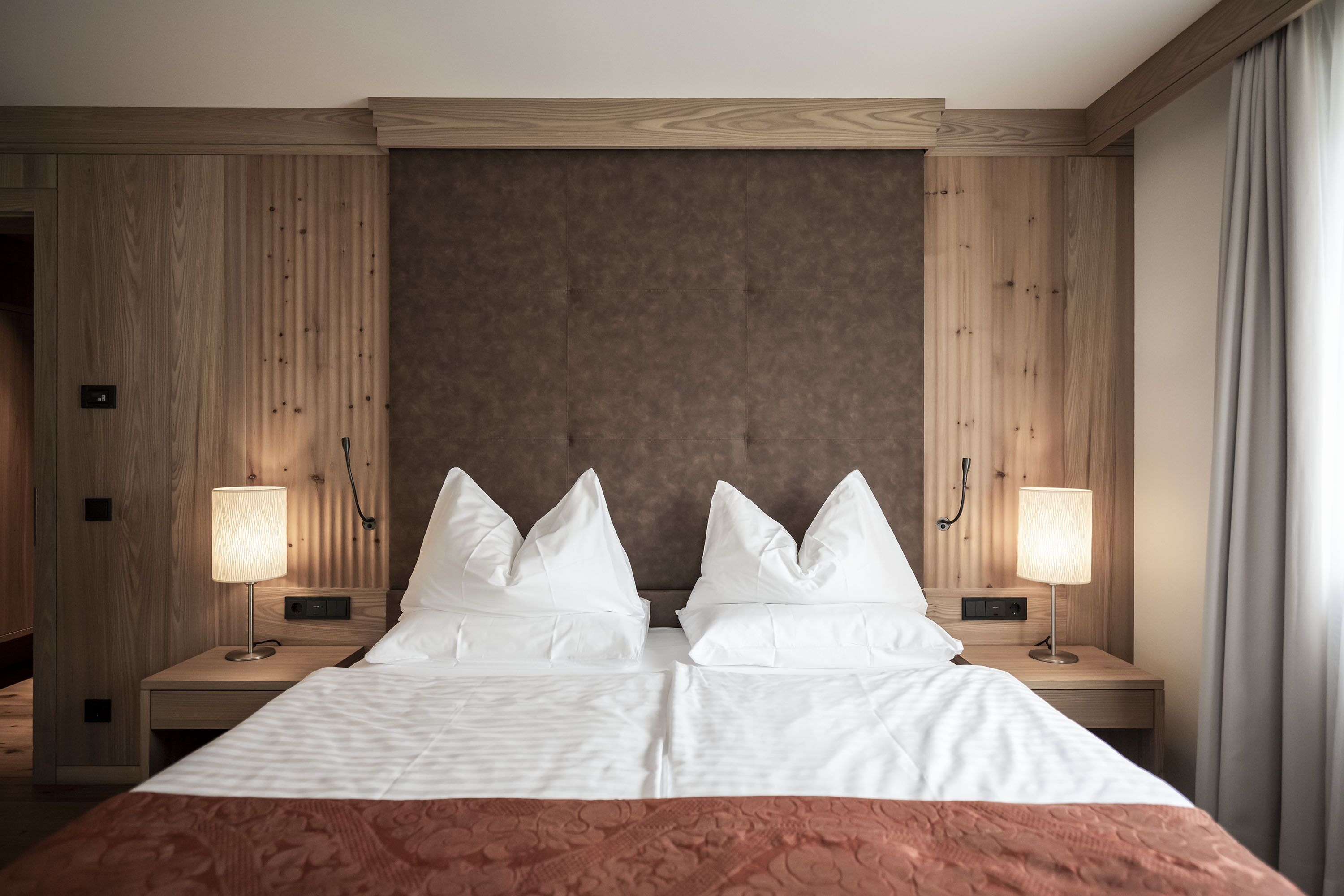 Una habitación de hotel con una cama grande, dos mesitas de noche y un cabecero.