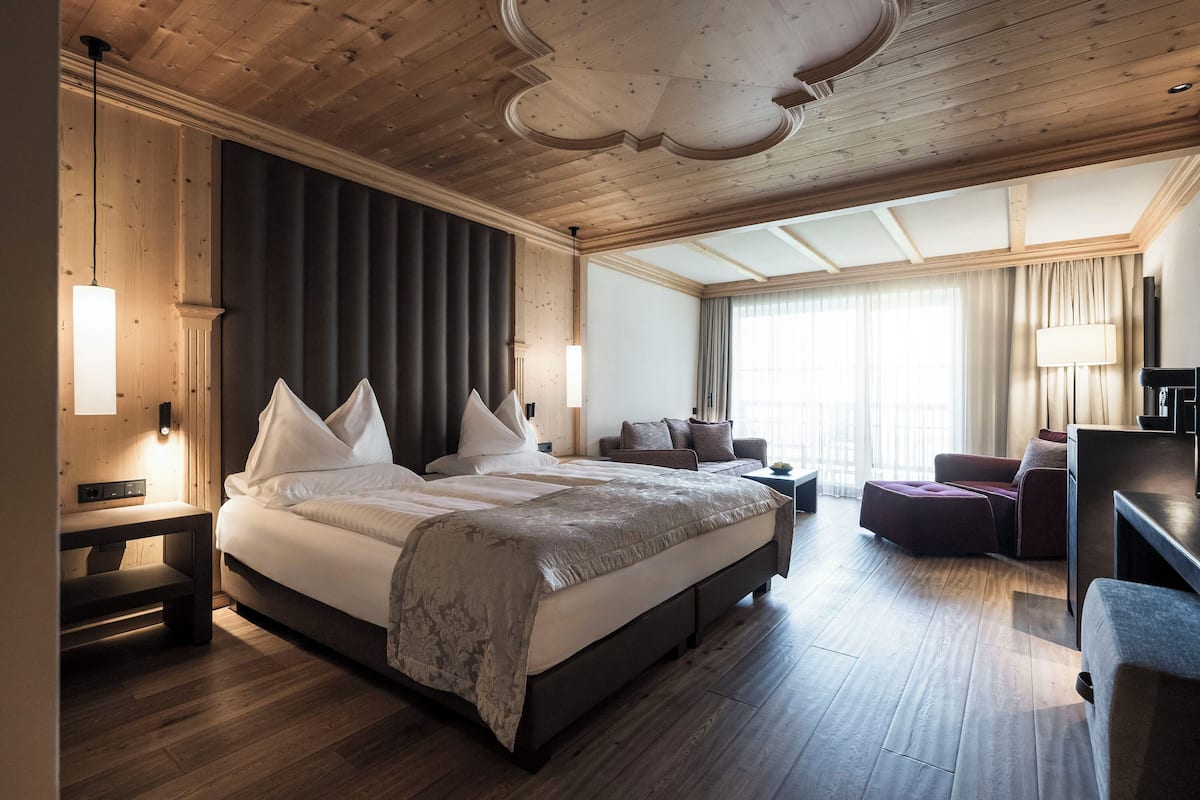 A spacious hotel room with a large bed, a seating area, and a view of the outdoors.