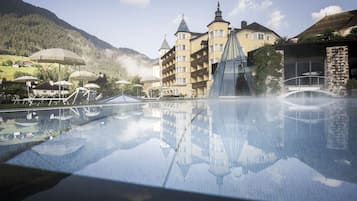 Una piscina techada, sombrillas, sillones reclinables de piscina