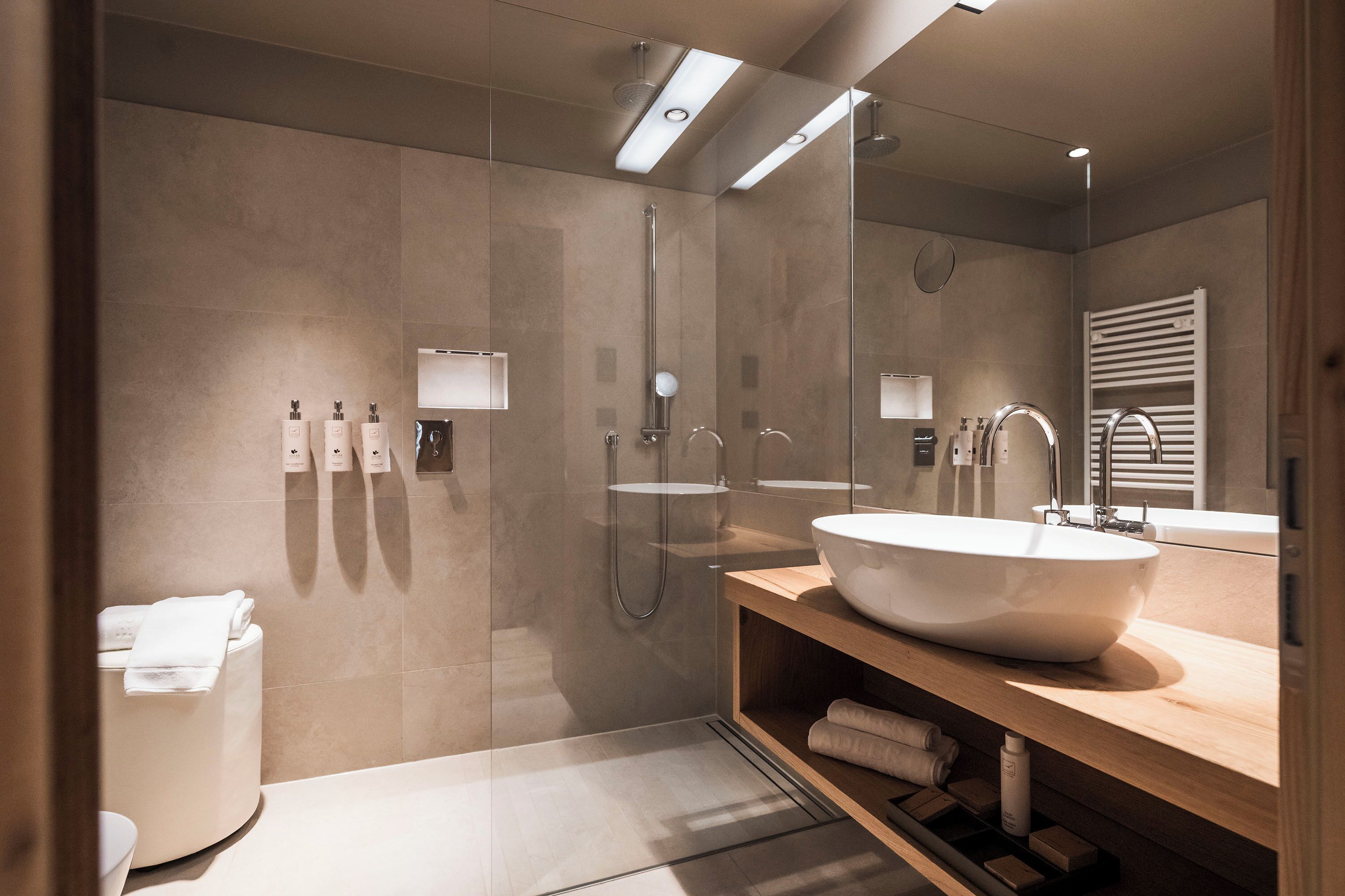 A modern bathroom with a large sink, a glass shower enclosure, and a wooden vanity.