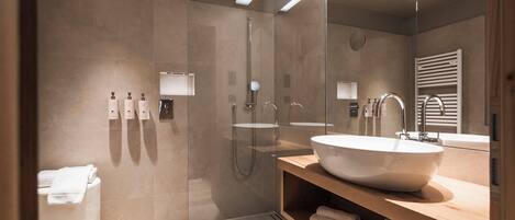 A modern bathroom with a large sink, a glass shower enclosure, and a wooden vanity.