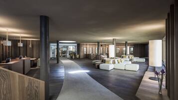 A spacious lobby with a central seating area, a reception desk, and large windows allowing natural light.