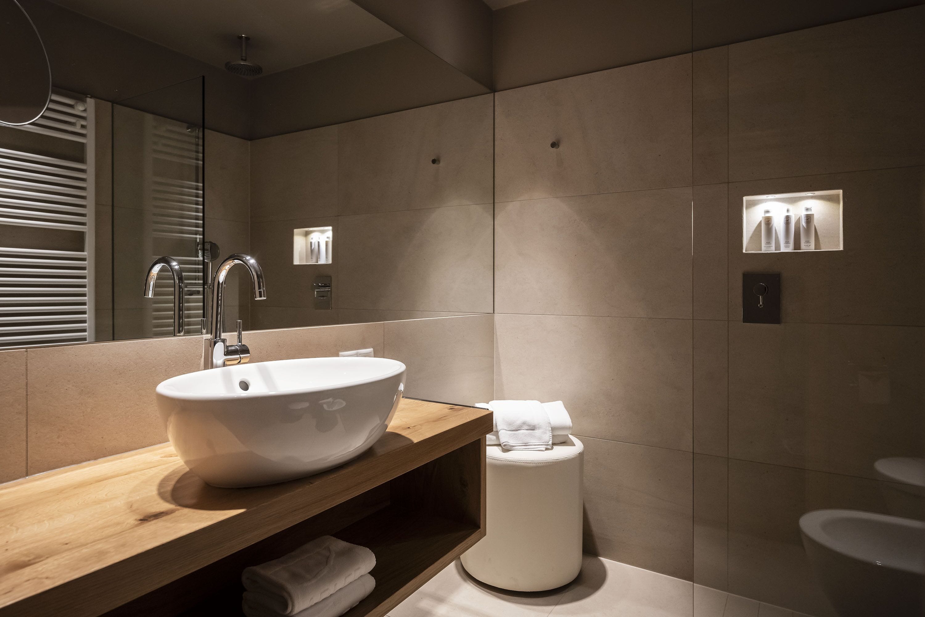 Un baño moderno con un lavabo grande blanco, tocador de madera y un inodoro.