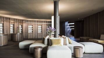 Um lobby moderno com uma coluna central, áreas de estar e painéis de madeira.