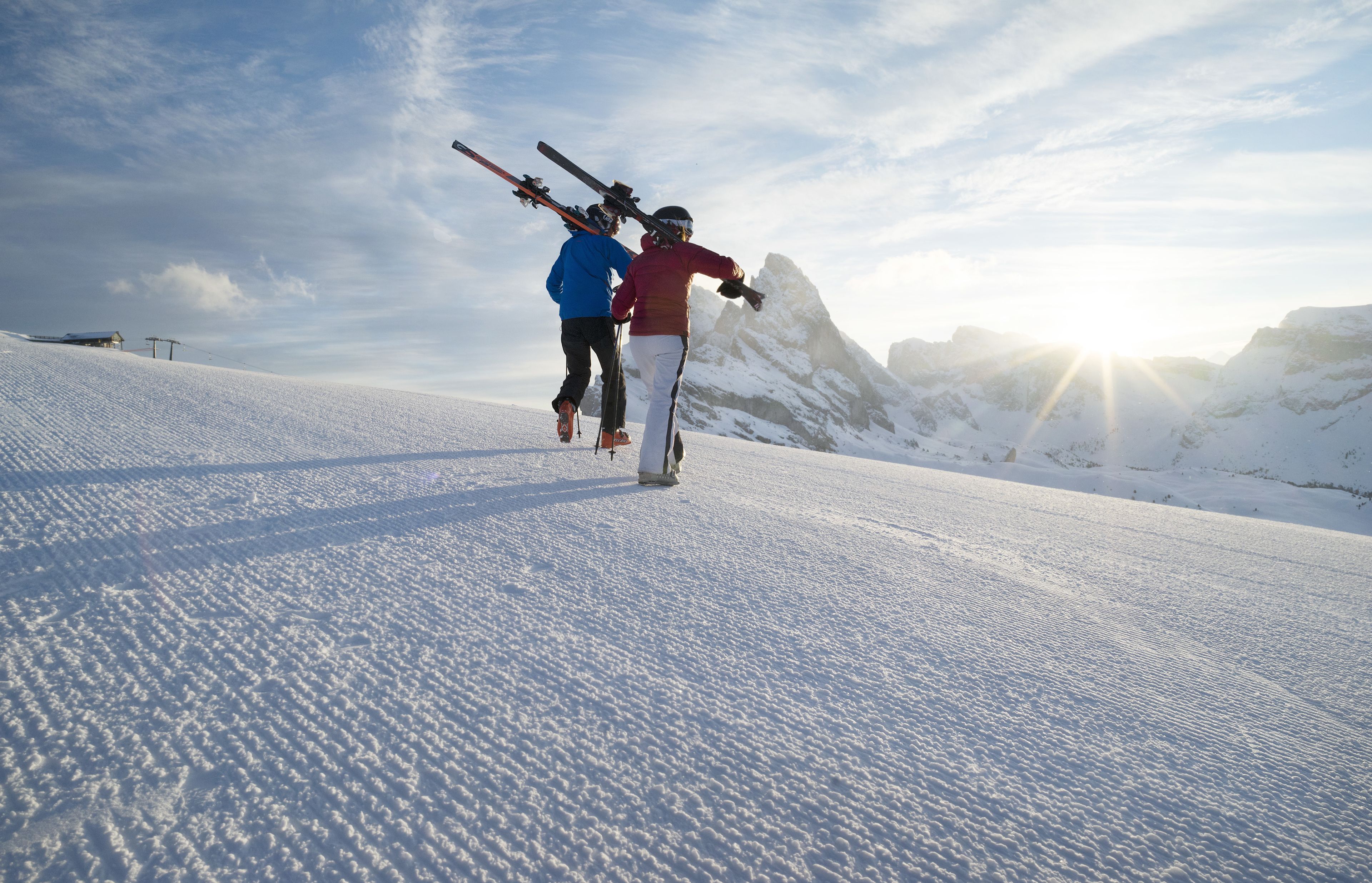 A snowy mountain slope with two skiers.