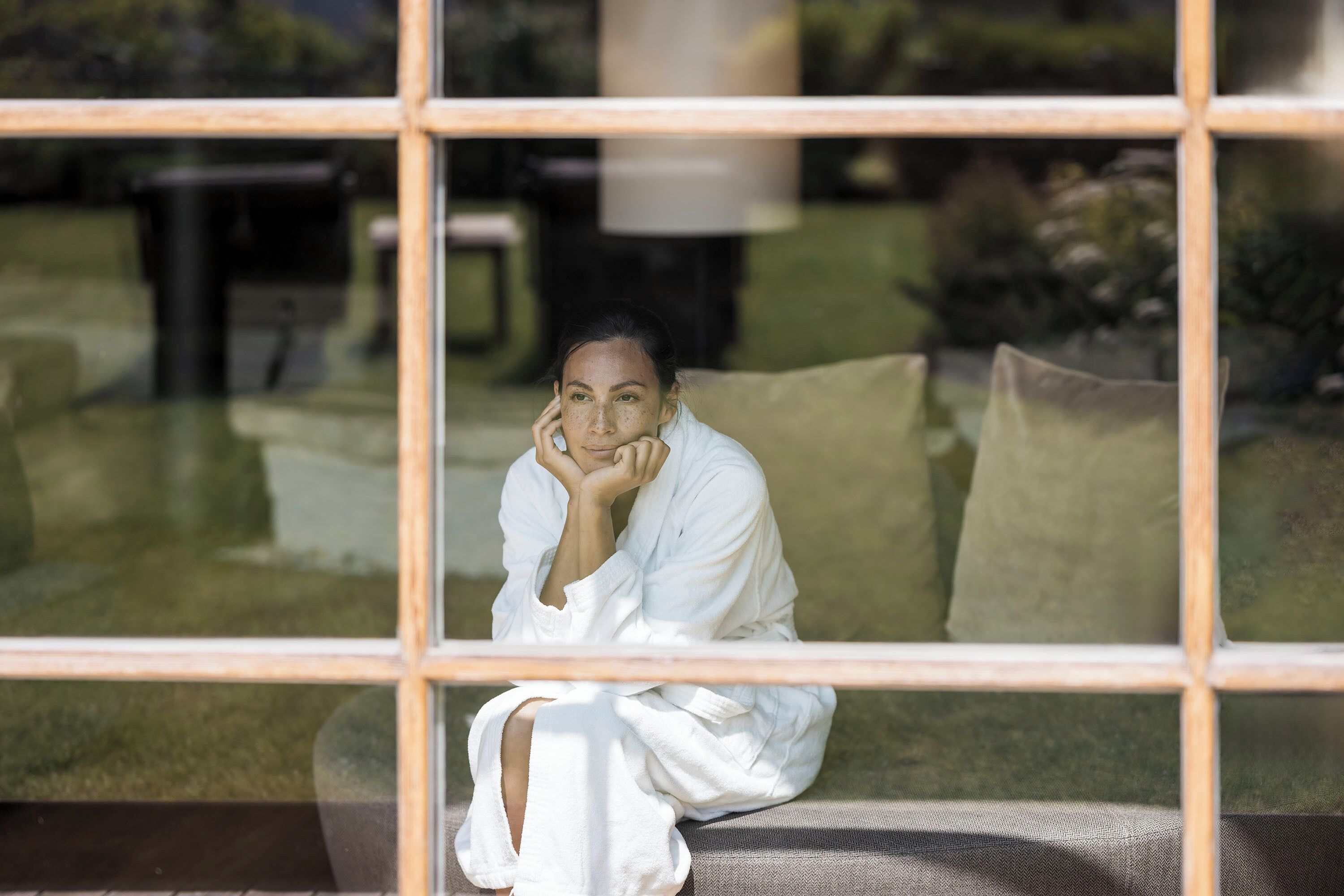 A person sitting on a couch in a room with a large window.