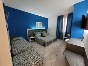 Habitación triple | Edredón, minibar, caja de seguridad en la habitación y escritorio 