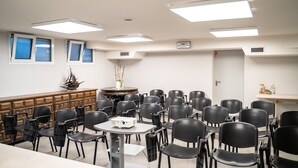 A conference room with multiple black chairs arranged around tables, a wooden cabinet, and a ship model on the wall. - Maritan Hotel & Spa (Padova)