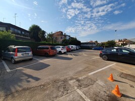Un estacionamiento con varios coches y algunos conos de seguridad naranja.