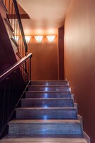 Eine Holztreppe mit Metallgeländern und Wandleuchten.
