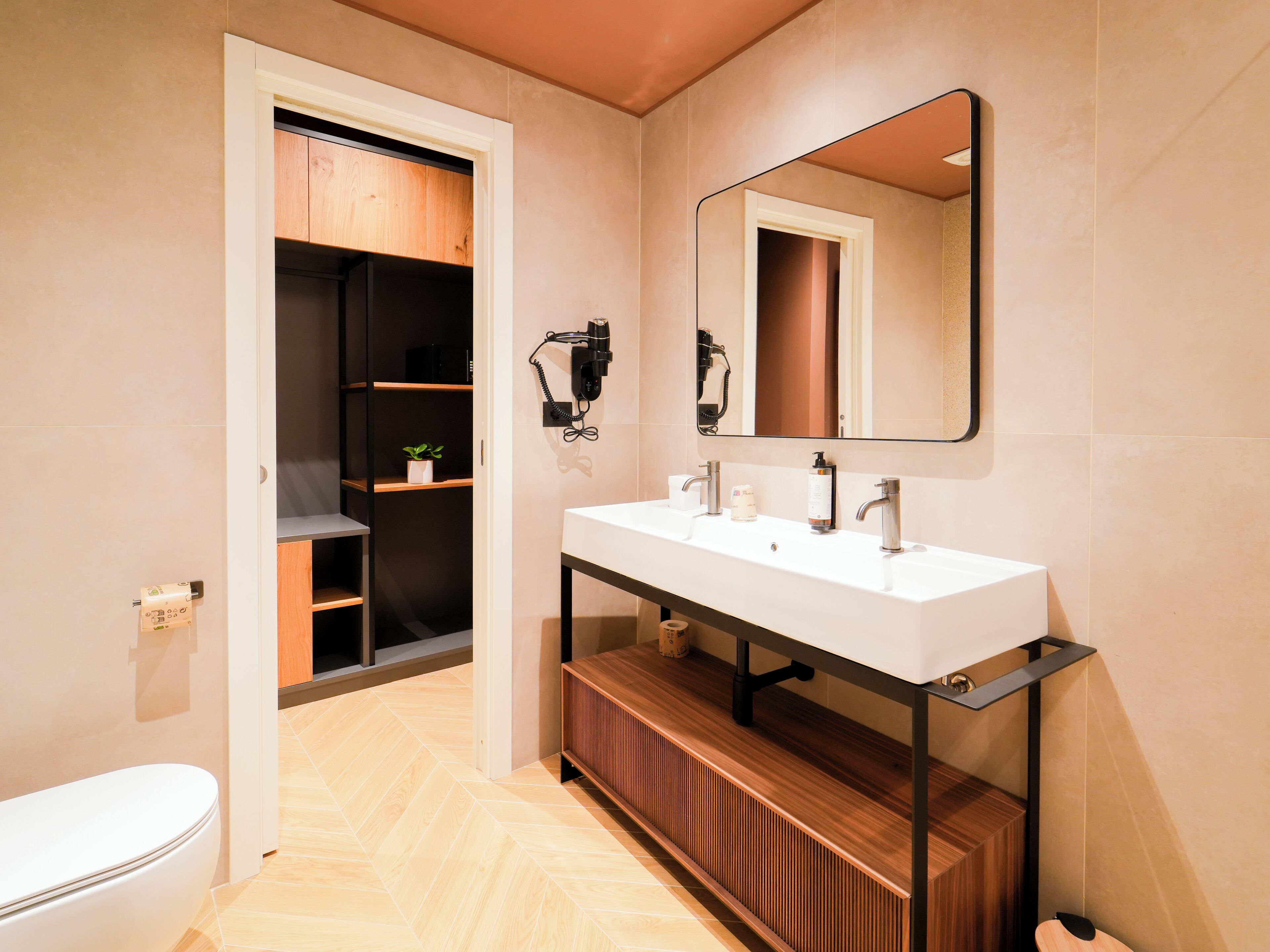 Ein modernes Badezimmer mit einem weißen Waschbecken, einem Spiegel und einem Holzwaschtisch.
