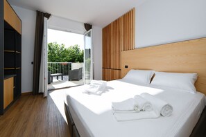 A modern hotel room with a large bed, a wooden headboard, and a balcony with outdoor furniture. - Best Western Hotel Arya (Sirmione)