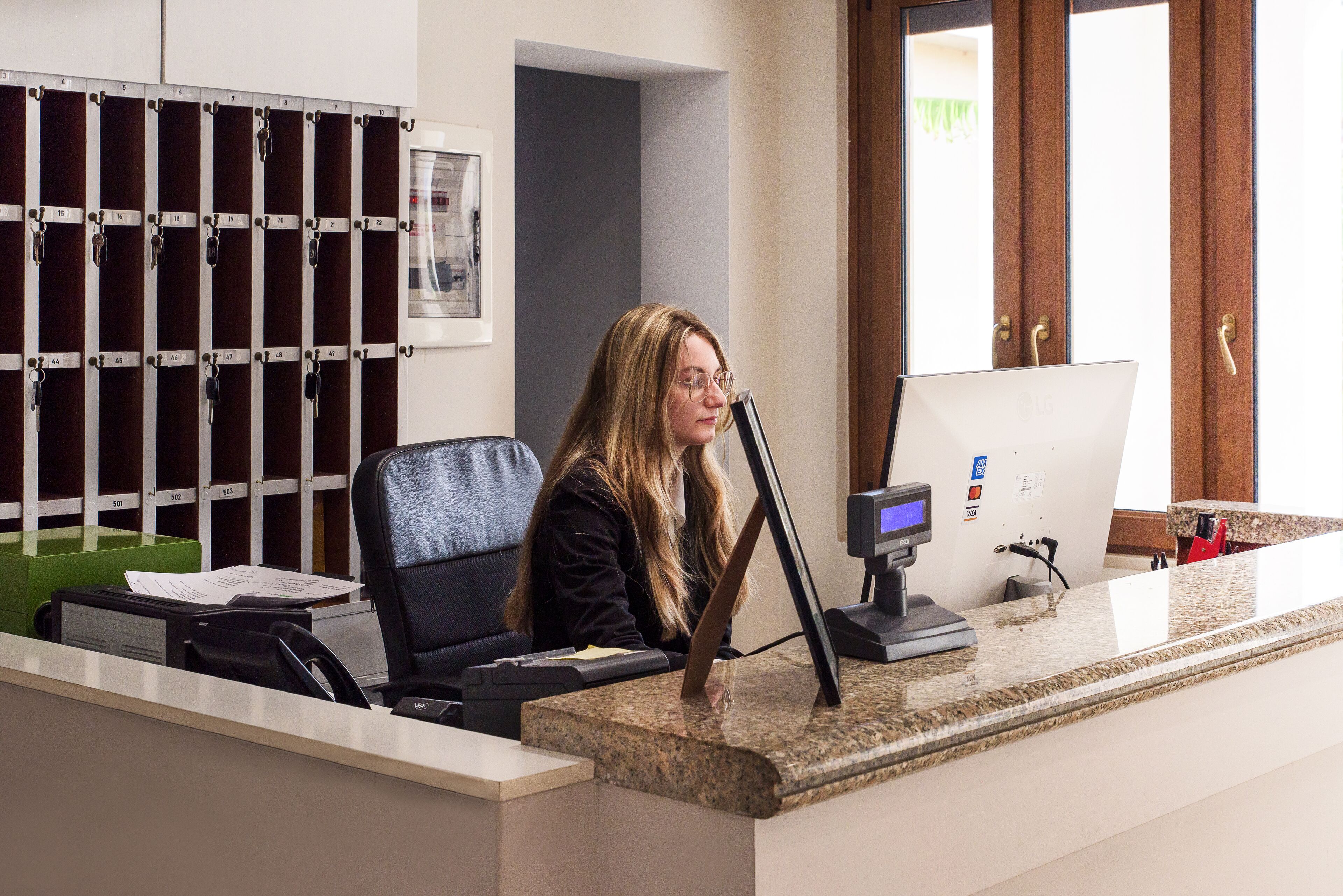 A reception desk with a computer, a chair, and a keycard holder in the background.