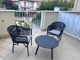Un balcone con due poltrone in vimini e un tavolino rotondo.