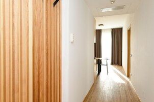 Un pasillo con paneles de madera en un lado, un interruptor de luz y una puerta al final.