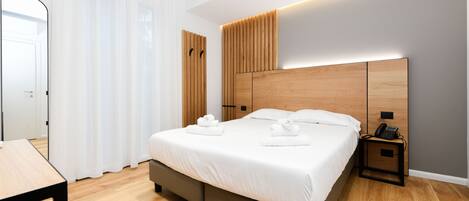 A modern bedroom with a large bed, wooden headboard, bedside tables, and a mirror.