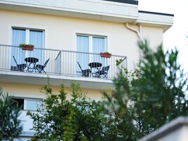 Un balcone con due sedie e un tavolo, ognuno decorato con una pianta in vaso.