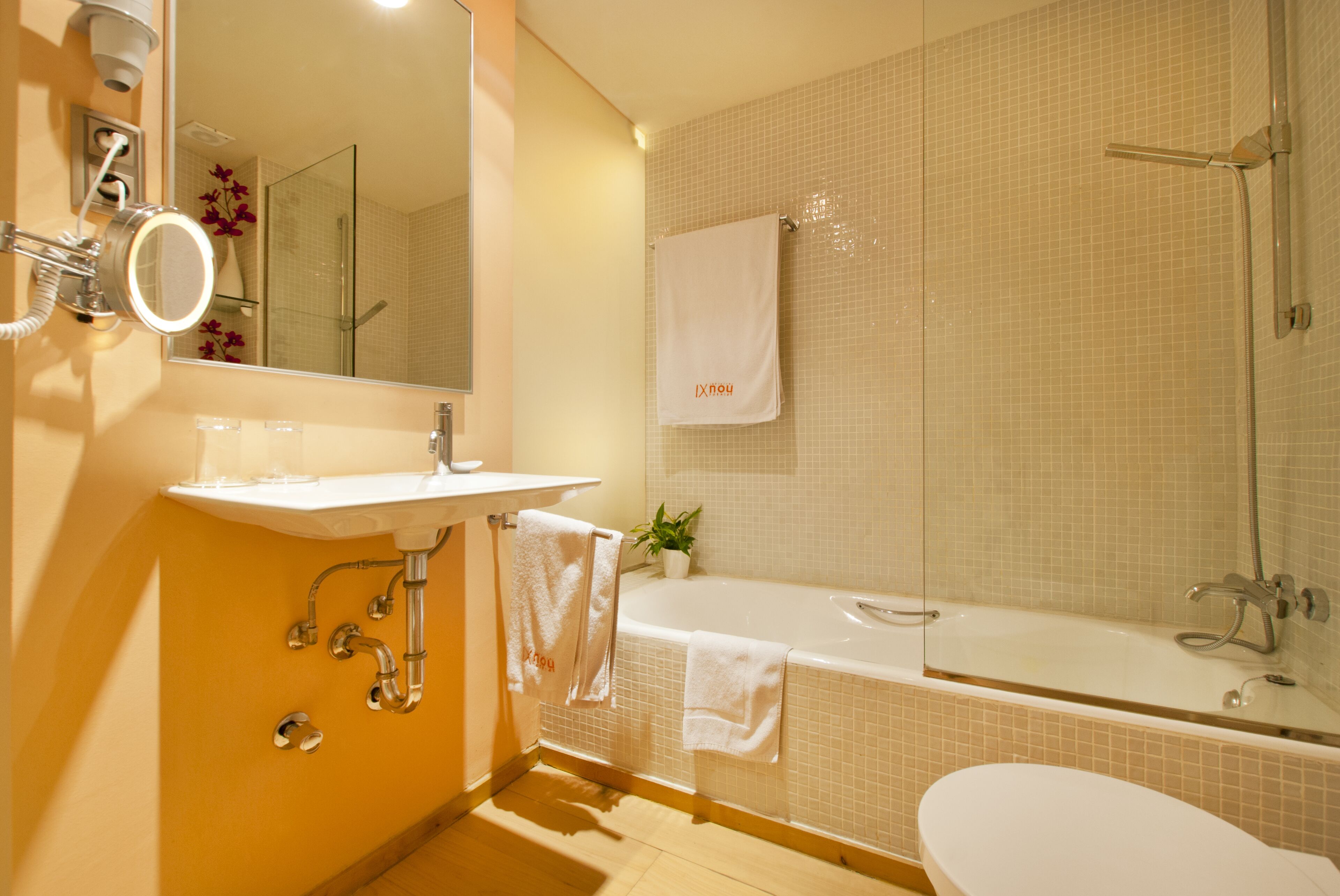 Un baño con lavamanos, espejo, toallero y bañera.