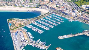 An aerial view of a marina with numerous boats docked, a pier, and surrounding buildings. - Cas Ferrer Nou Hotelet (Alcúdia)