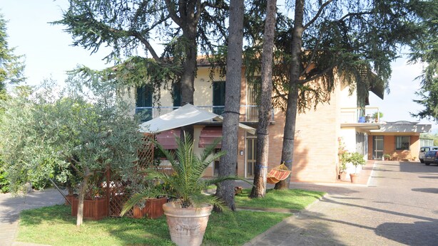 A residential building with a paved driveway, a large potted plant, and a hammock. - Marinetta Bed & Breakfast (Signa)