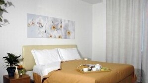 A hotel room with a bed, a nightstand, a potted plant, and a painting on the wall. - Marinetta Bed & Breakfast (Signa)