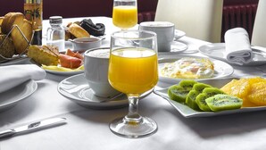 Una escena de desayuno con una mesa, platos y un vaso de jugo de naranja.