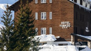 Un edificio de madera identificado con la señal “HOTEL TOBAZO”, con montañas al fondo.
